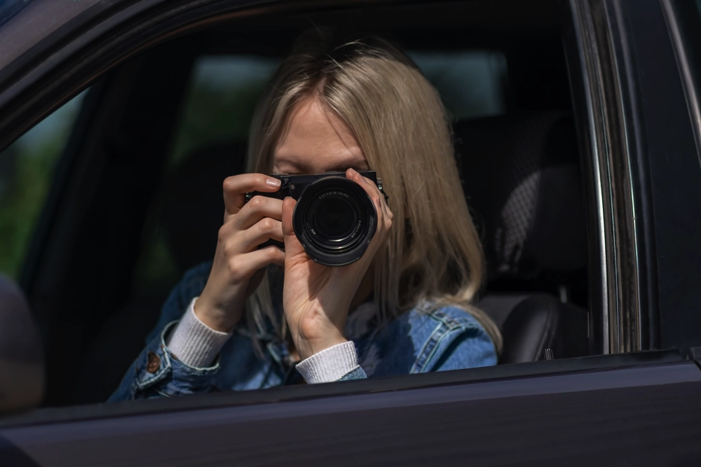 close up of woman with camera taking picture in car with window rolled down
